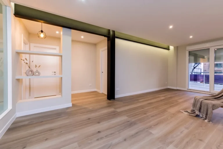 Salón reformado en calle del Marqués de Zafra, Madrid, con viga estructural negra, suelo de madera y terraza | Global Oltenia