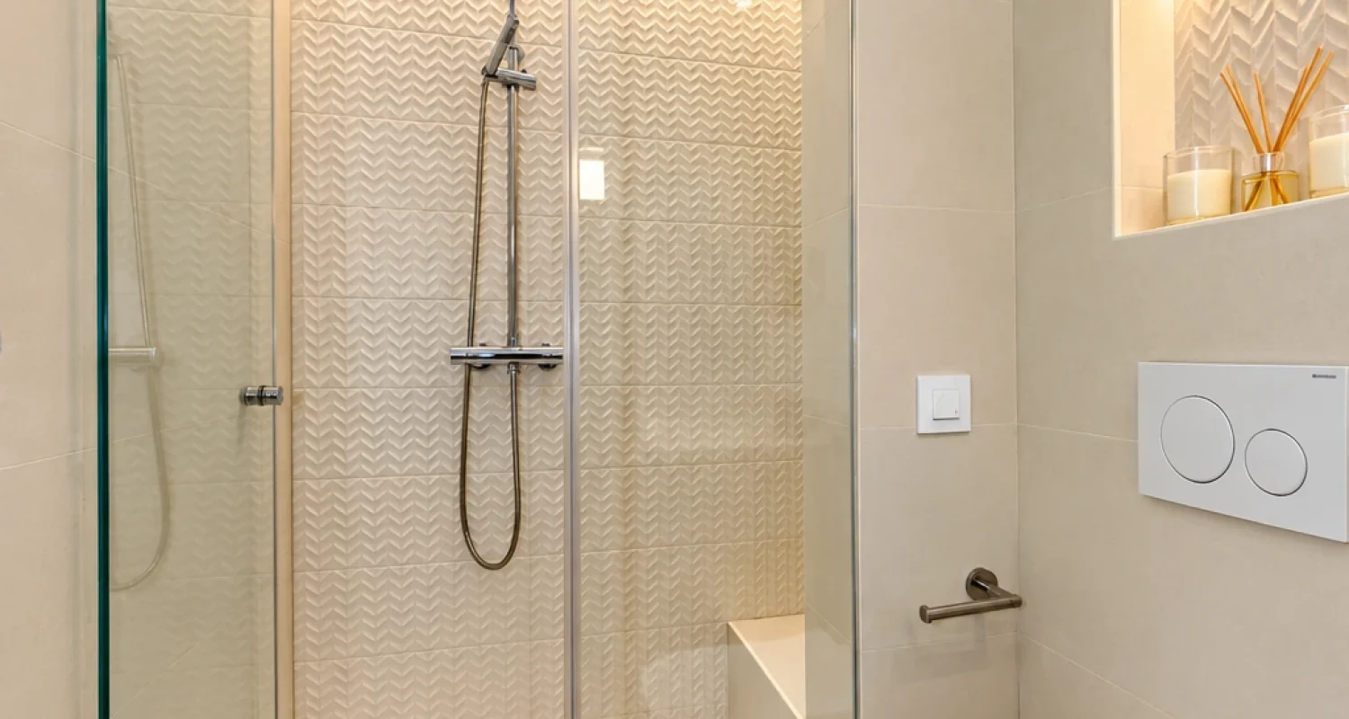 Cuarto de baño con ducha y hornacinas iluminadas tras reforma integral en calle Doctor Casal Madrid por Global Oltenia