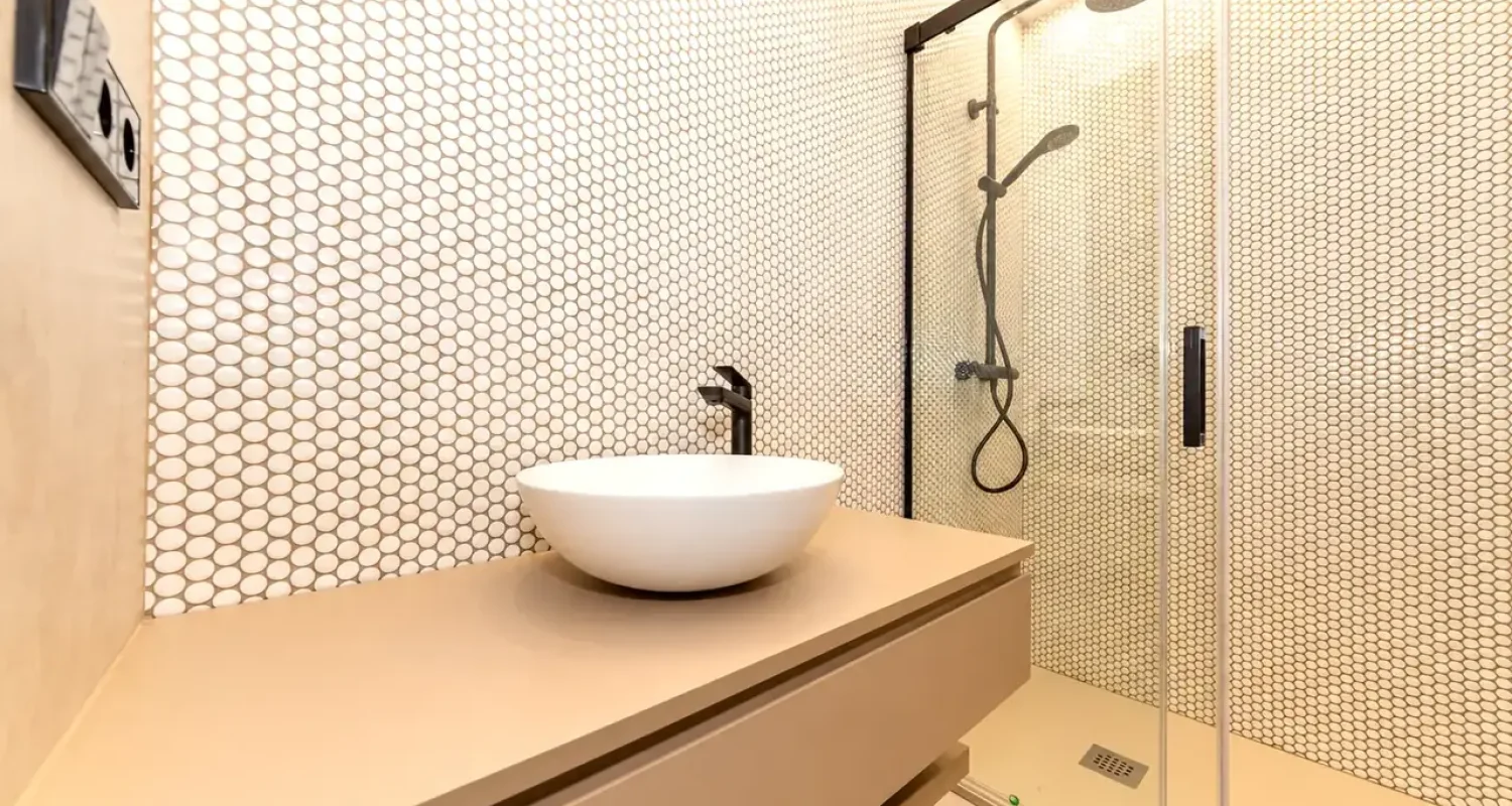 Baño reformado en Calle Tarragona, Madrid, con mosaico claro, lavabo sobre encimera y ducha con mampara de vidrio