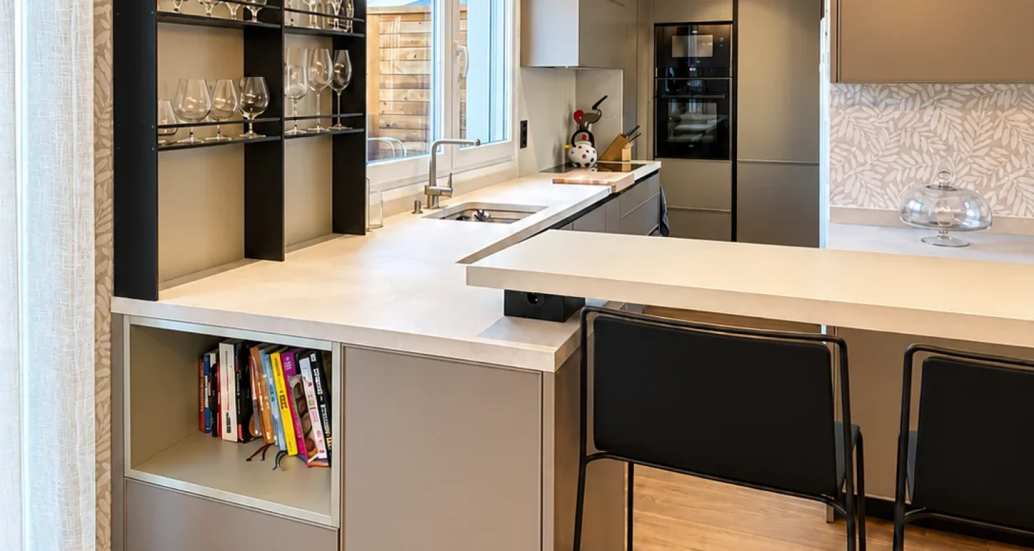 Cocina reformada en ático de Aviador Zorita, Madrid, con vitrina acristalada para copas, barra y taburetes.