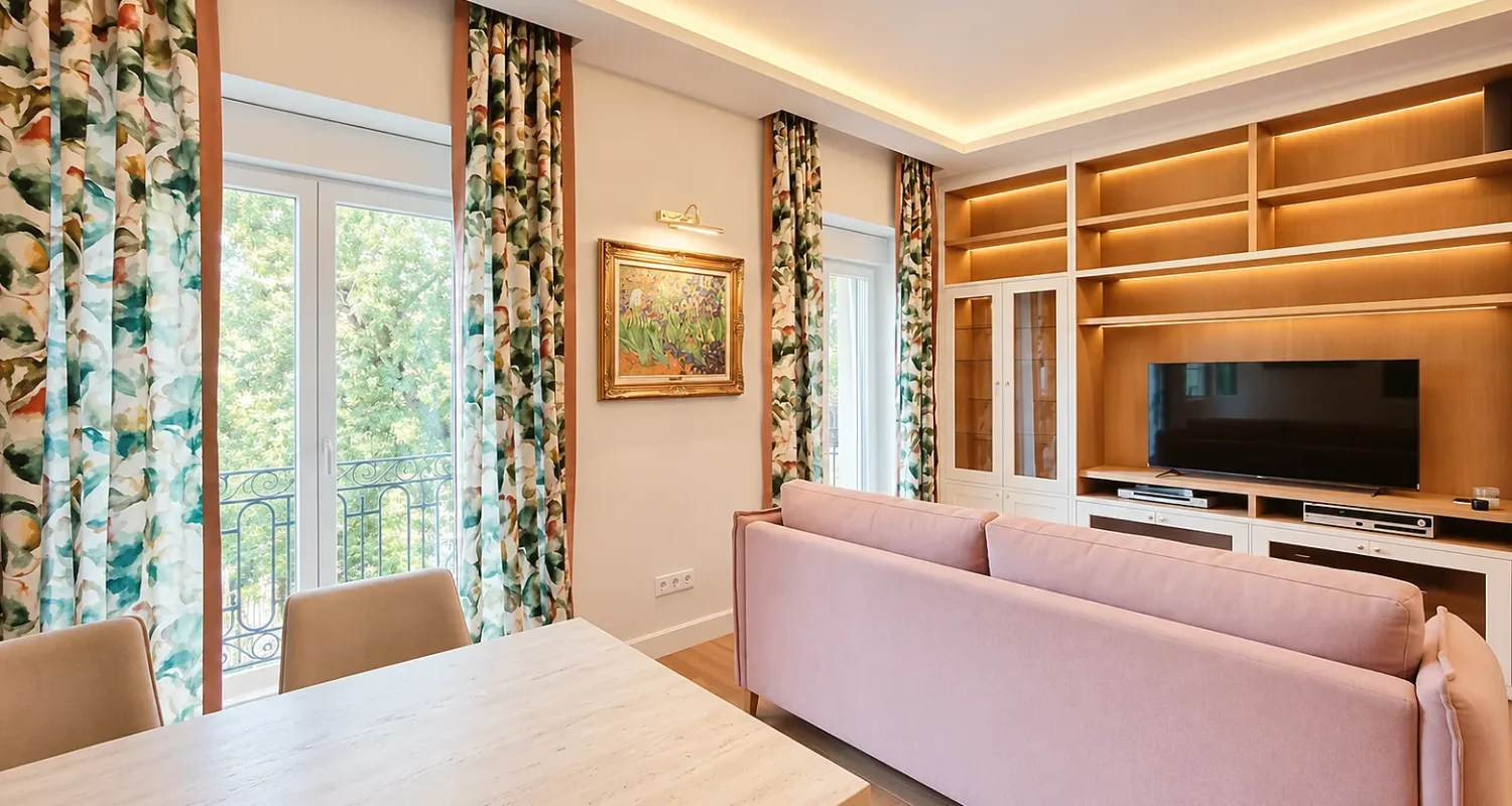 Salón de la reforma integral de piso en Alonso Cano, Madrid, con mueble de TV a medida, sofá rosa e iluminación LED indirecta.