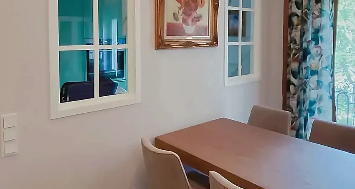 Comedor de la reforma integral de piso en Alonso Cano, Madrid, con mesa de madera, sillas tapizadas y ventanas interiores acristaladas.