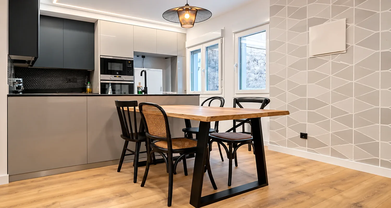 Cocina abierta al comedor en reforma integral de Calle Tarragona, Madrid, con mesa de madera e iluminación LED