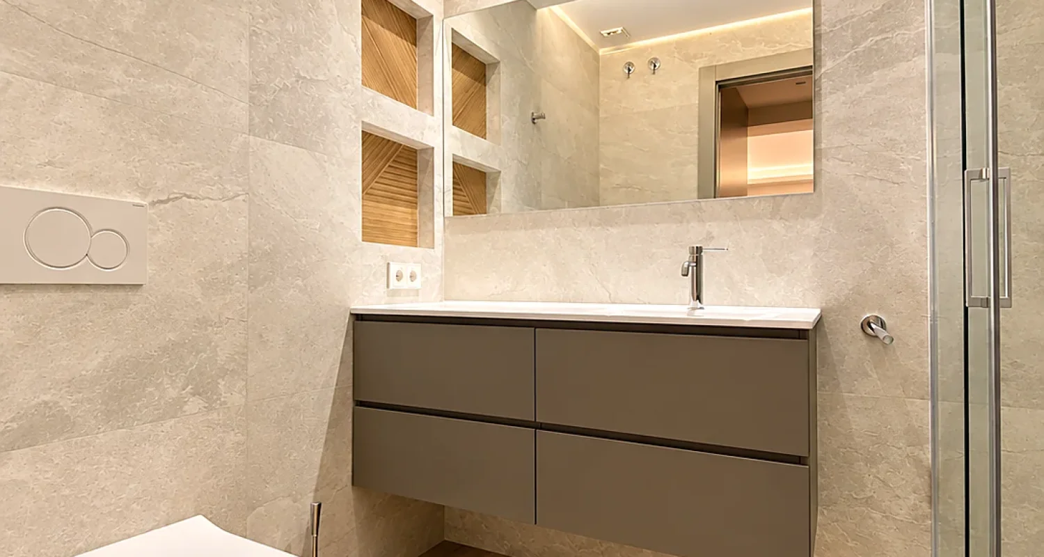 Baño reformado en chalet de Daganzo con mueble gris suspendido, inodoro suspendido y mampara de ducha de cristal.