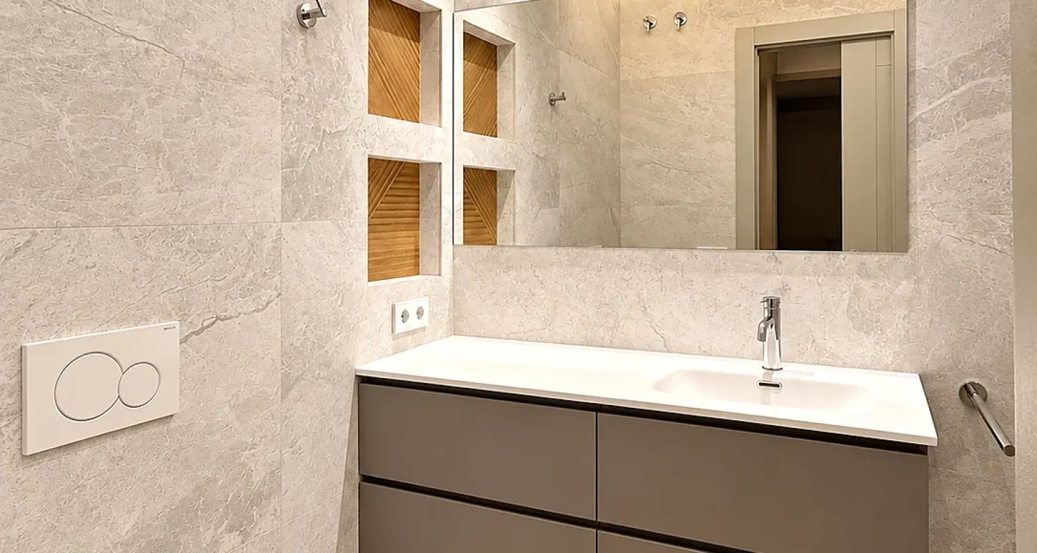 Baño reformado en chalet de Daganzo con mueble de lavabo suspendido, espejo grande e iluminación indirecta.
