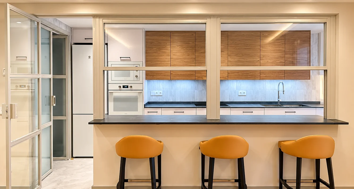 Cocina reformada con barra de desayuno, tres taburetes e iluminación LED integrada en chalet de Daganzo, Madrid.