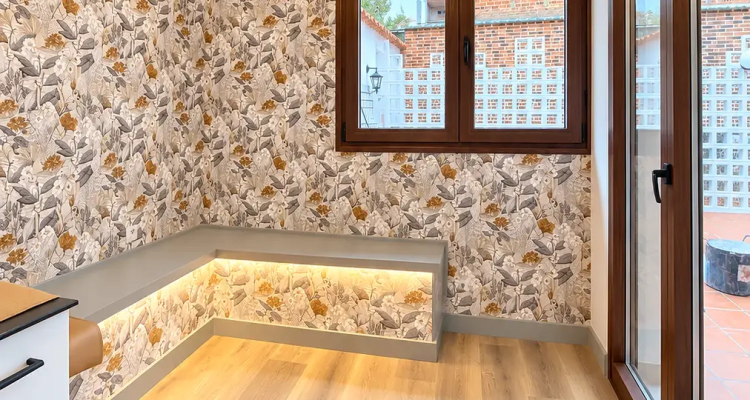 Rincón de lectura con banco junto a la ventana, iluminación LED y papel decorativo en chalet reformado de Daganzo.