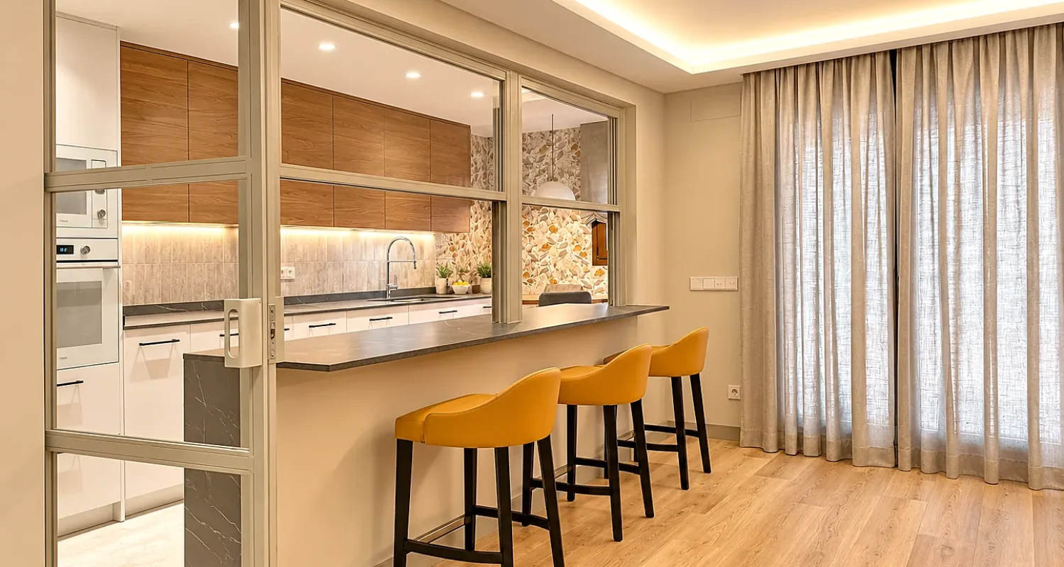 Salón con barra de cocina y taburetes en reforma integral de chalet en Daganzo, Madrid.