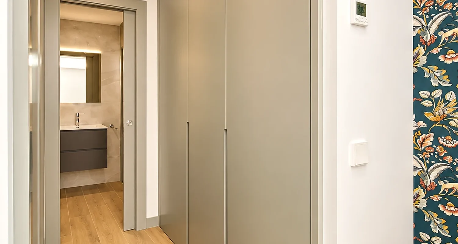 Vestidor con armarios a medida en color gris y acceso al baño en reforma integral de chalet en Daganzo de Arriba, Madrid.